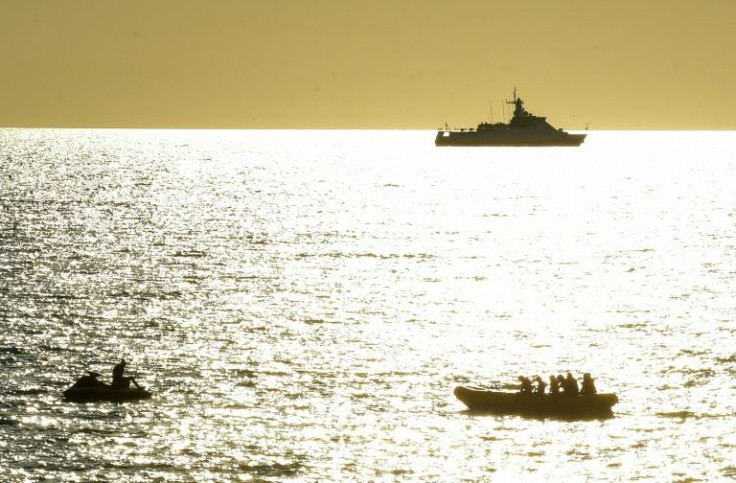 A Sebastopoli, la città più grande della Crimea e sede della flotta russa del Mar Nero, le navi da guerra russe sono visibili mentre i bagnanti si rinfrescano in mareÂ