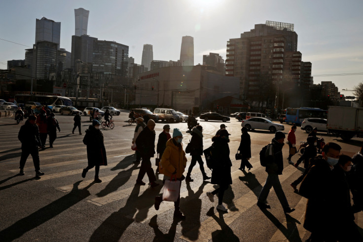 Le persone attraversano una strada durante l&#39;ora di punta mattutina di fronte allo skyline del CBD a Pechino