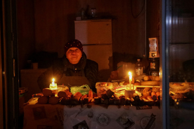 Un venditore attende i clienti in un piccolo negozio, illuminato da candele durante un&#39;interruzione di corrente, dopo che un&#39;infrastruttura civile critica è stata colpita da attacchi missilistici russi a Odessa