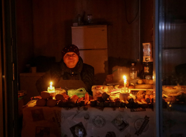Un venditore attende i clienti in un piccolo negozio, illuminato da candele durante un&#39;interruzione di corrente, dopo che un&#39;infrastruttura civile critica è stata colpita da attacchi missilistici russi a Odessa