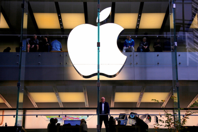 Un cliente si trova sotto un logo Apple illuminato mentre guarda fuori dalla vetrina dell&#39;Apple store situato nel centro di Sydney