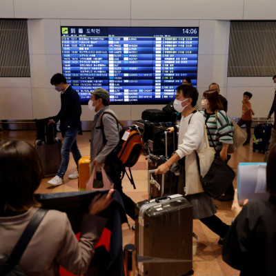 I passeggeri camminano al loro arrivo all&#39;aeroporto internazionale di Haneda mentre il Giappone riapre per i viaggi senza visto a Tokyo