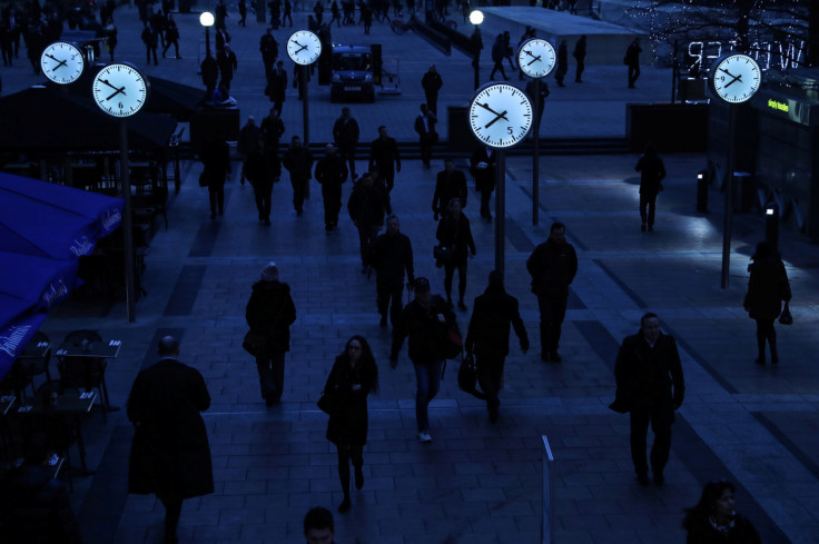 I lavoratori camminano per andare al lavoro durante l&#39;ora di punta mattutina nel quartiere finanziario di Canary Wharf a Londra