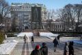 La gente cammina in un parco vicino al monumento del poeta ucraino Taras Shevchenko coperto da una costruzione protettiva per proteggersi dai bombardamenti nel centro di Kiev