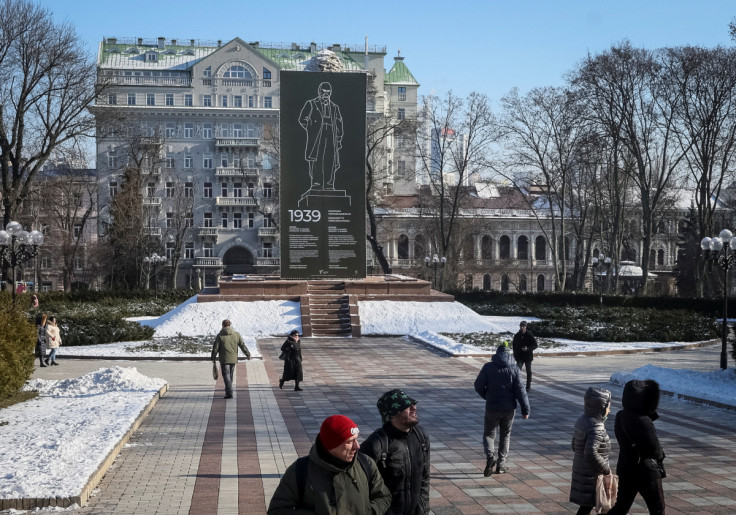 La gente cammina in un parco vicino al monumento del poeta ucraino Taras Shevchenko coperto da una costruzione protettiva per proteggersi dai bombardamenti nel centro di Kiev
