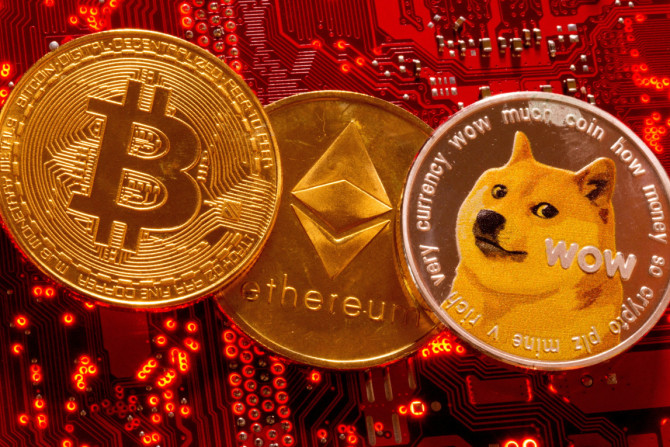 Le rappresentazioni delle criptovalute Bitcoin, Ethereum e DogeCoin sono posizionate sulla scheda madre del PC in questa illustrazione presa