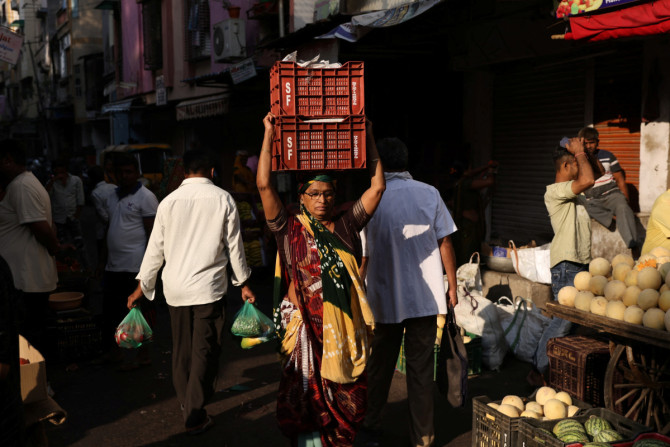 Una donna porta scatole di verdure sulla testa in un mercato di Ahmedabad