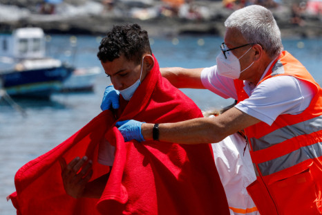 Un membro della Croce Rossa assiste un migrante dopo lo sbarco da una nave della guardia costiera spagnola, al porto di Arguineguin