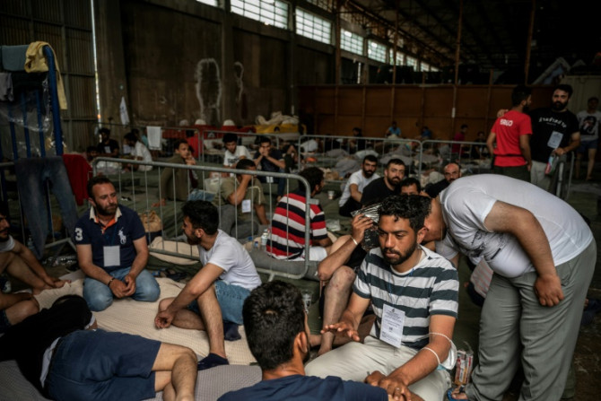 I sopravvissuti all&#39;affondamento siedono all&#39;interno di un magazzino nel porto di Kalamata in Grecia